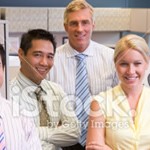 stock-photo-16665659-business-team-standing-in-cubicle-smiling
